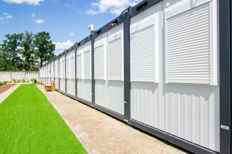Exterior view of modern container homes with metal siding and adjacent landscaped yard.
